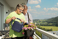 Senioren gießen Blumen auf dem Balkon. Szene: DRK-Wohngemeinschaft "Ruhrtalblick"